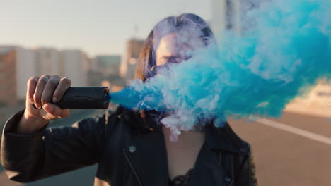 young woman holding blue smoke bomb in city at sunrise