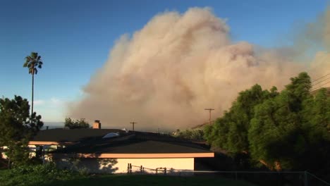 plano general de una pared de humo que se eleva desde los incendios forestales alrededor de una comunidad del sur de california