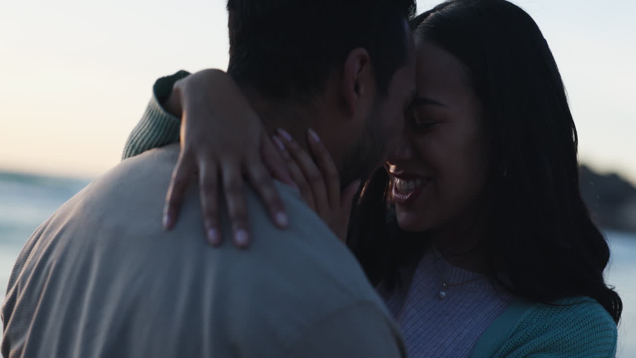 Love, sunset and kiss with couple at beach