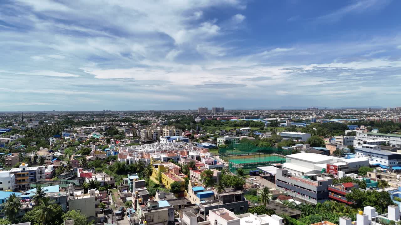 Sprawling Indian Metro: Wide aerial panoramic shot of a low-to-mid-rise South Asian city under a dramatic sky. The scene shows dense urban development, residential areas, and a distant city skyline