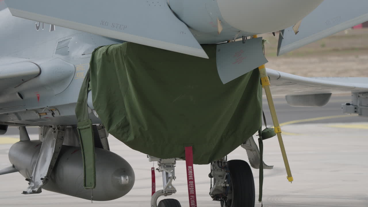 Pilota militare che ispeziona un jet da combattimento sul piazzale.
