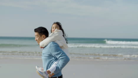 그의 딸과 함께 해변을 따라 걷고 그녀의 이야기를 들려주는 일본인 아버지