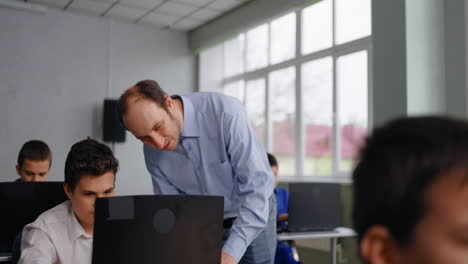 maestro ayudando al estudiante con una computadora portátil en el aula