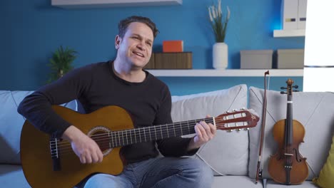 happy musician man playing his guitar at home smiling happily, enjoying his violin.