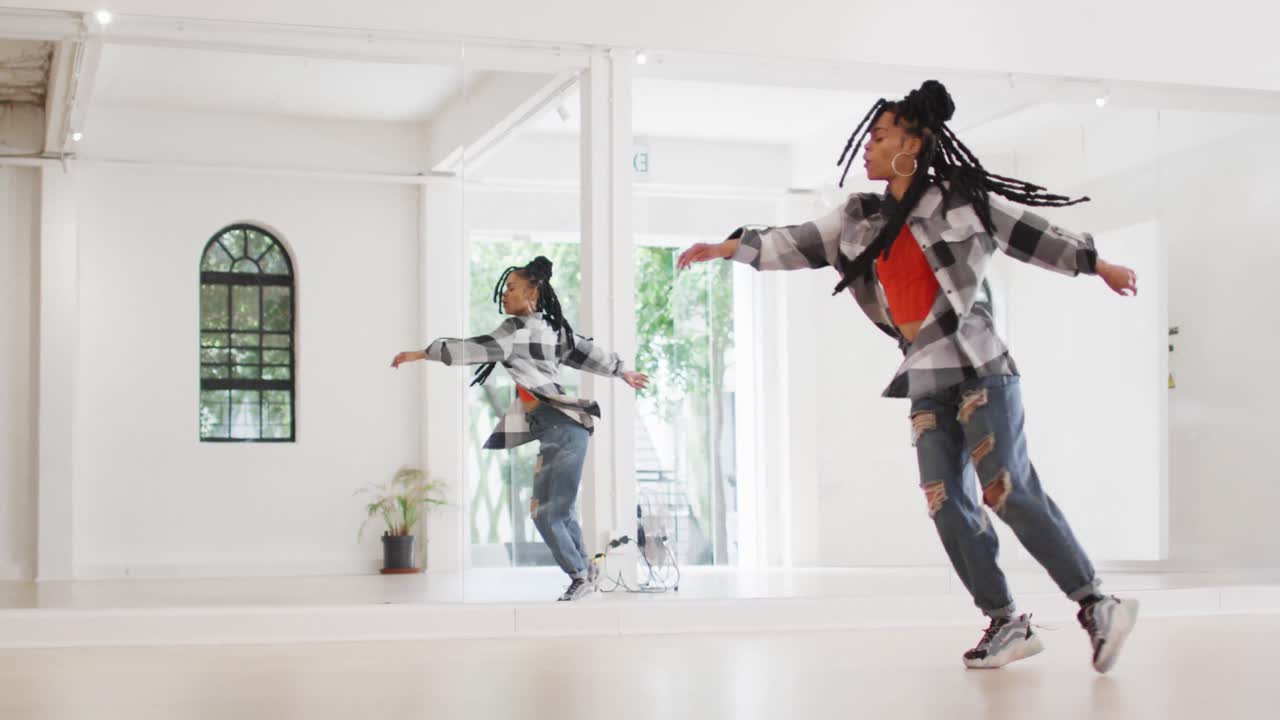 ballerina bi-razziale che balla da sola davanti allo specchio in uno studio di danza, slow motion