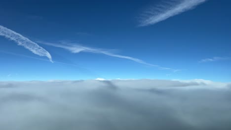 Awesome-view-from-a-jet-cabin-flying-over-a-sea-of-clouds-with-a-deep-blue-sky-with-some-jet-wakes-ahead