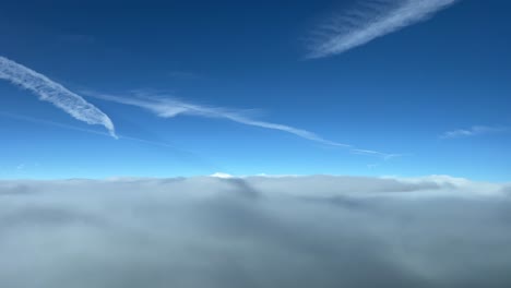 awesome view from a jet cabin flying over a sea of clouds with a deep blue sky with some jet wakes ahead