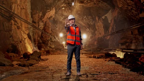 full body of asian male engineer with safety helmet disapproving with no hand sign while standing in underground mine tunnel