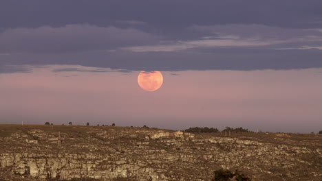 Rise-of-a-full-glowing-red-moon-with-clouds-above-the-horizon-of-the-earth