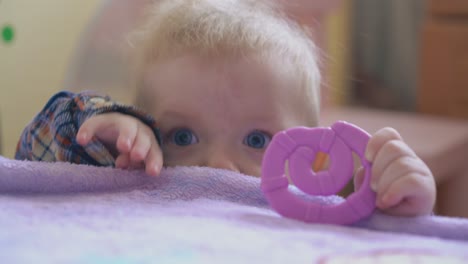 baby in warm shirt nibbles teether climbing on soft bed