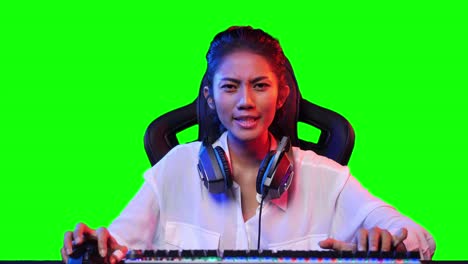 asian gamer woman playing game online and looking at screen on pc computer at home. asian woman controlling console with mouse and keyboard. green screen or chroma key background.