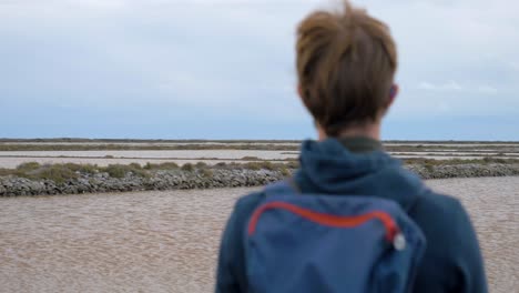 Slow-motion-orbiting-shot-of-a-young-man-looking-out-at-the-Sete-salt-flats