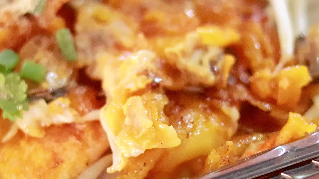 A detailed view of crispy noodles garnished with fresh herbs and savory toppings.