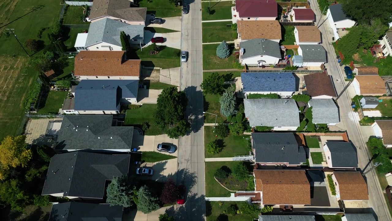 High altitude aerial drone shot moving over a residential neighbourhood with tree-lined streets, homes, and rooftops stretching across Winnipeg on a summer day