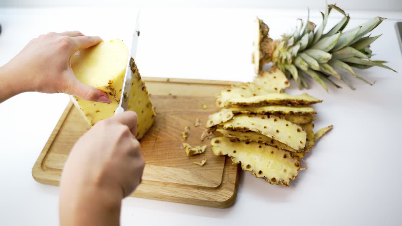 Hands slicing pineapple. Hands of woman peeling pineapple with knife