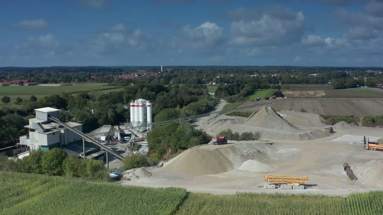 Luftaufnahme über einer Baustelle mit einem arbeitenden Bagger und Sandhügeln