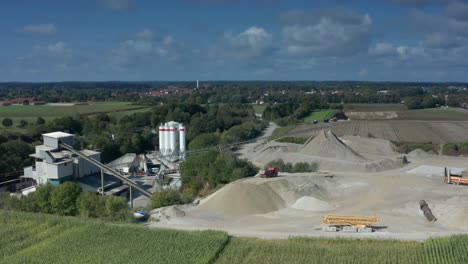 Aerial-view-over-a-construction-site-with-a-working-excavator-and-hills-of-sand