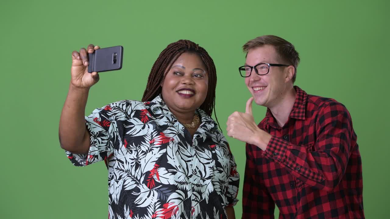 Donna africana in sovrappeso e giovane uomo scandinavo insieme su sfondo verde