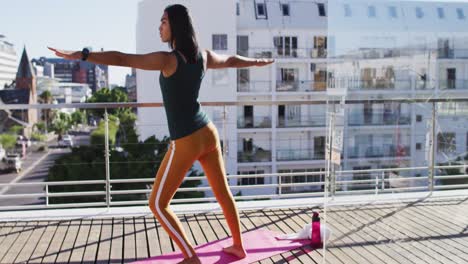 Mixed-race-gender-fluid-person-practicing-yoga-meditation-on-roof-terrace