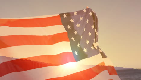 man holding american flag and sunset