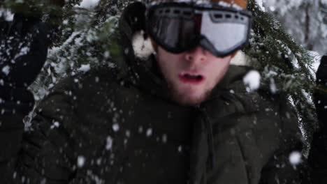 Joven-Irrumpe-A-Través-De-Una-Rama-De-árbol-Cubierto-De-Nieve-En-Cámara-Lenta