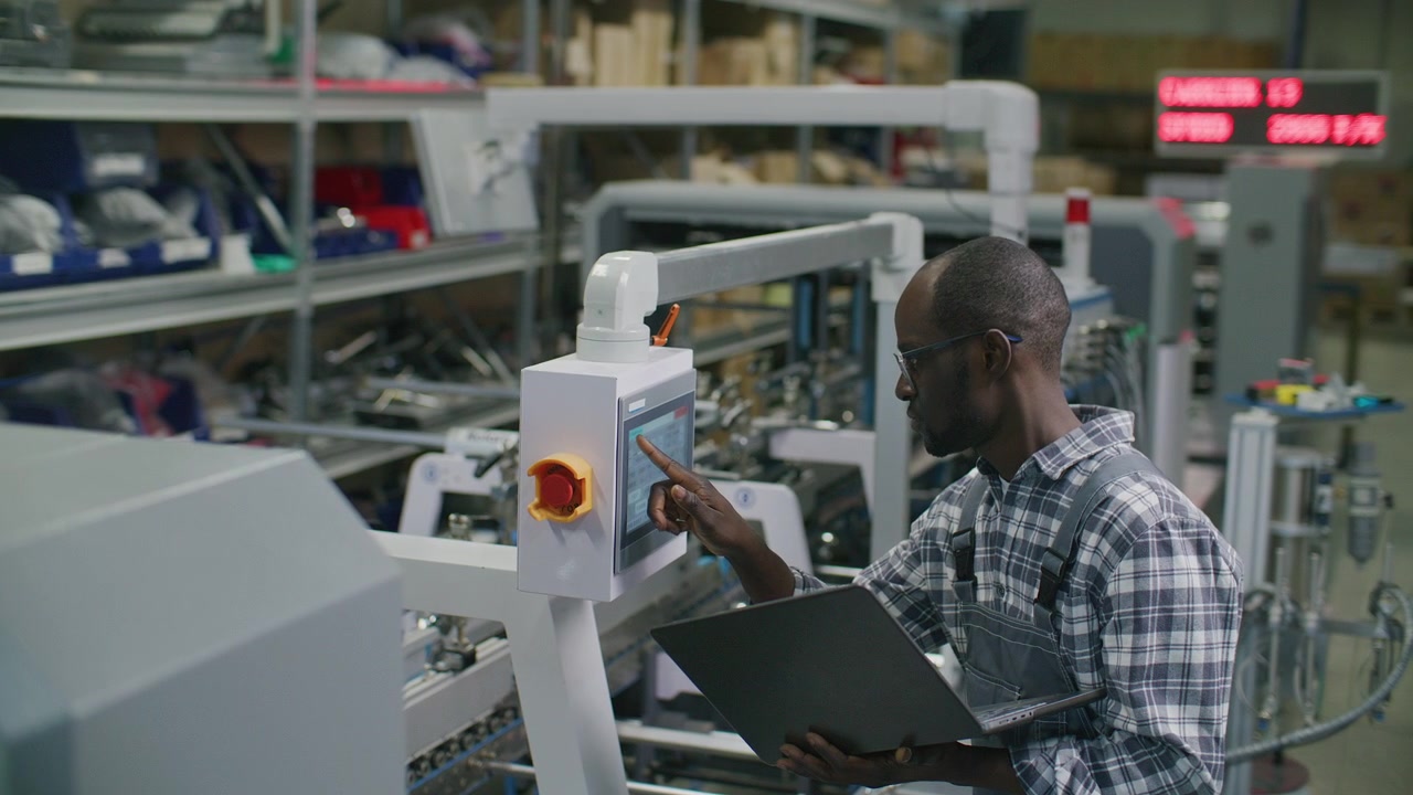 Printing Factory Engineer Using Laptop and Control Panel on Production Line