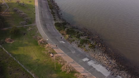 Aerial-tracking-shot-of-person-riding-bicycle-at-waterfront-of-River-Plate-in-Buenos-Aires