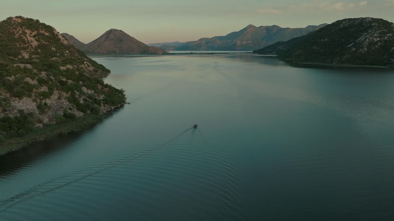 A boat gliding across skadar lake in montenegro at sunset, aerial view