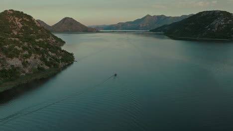 a boat gliding across skadar lake in montenegro at sunset, aerial view