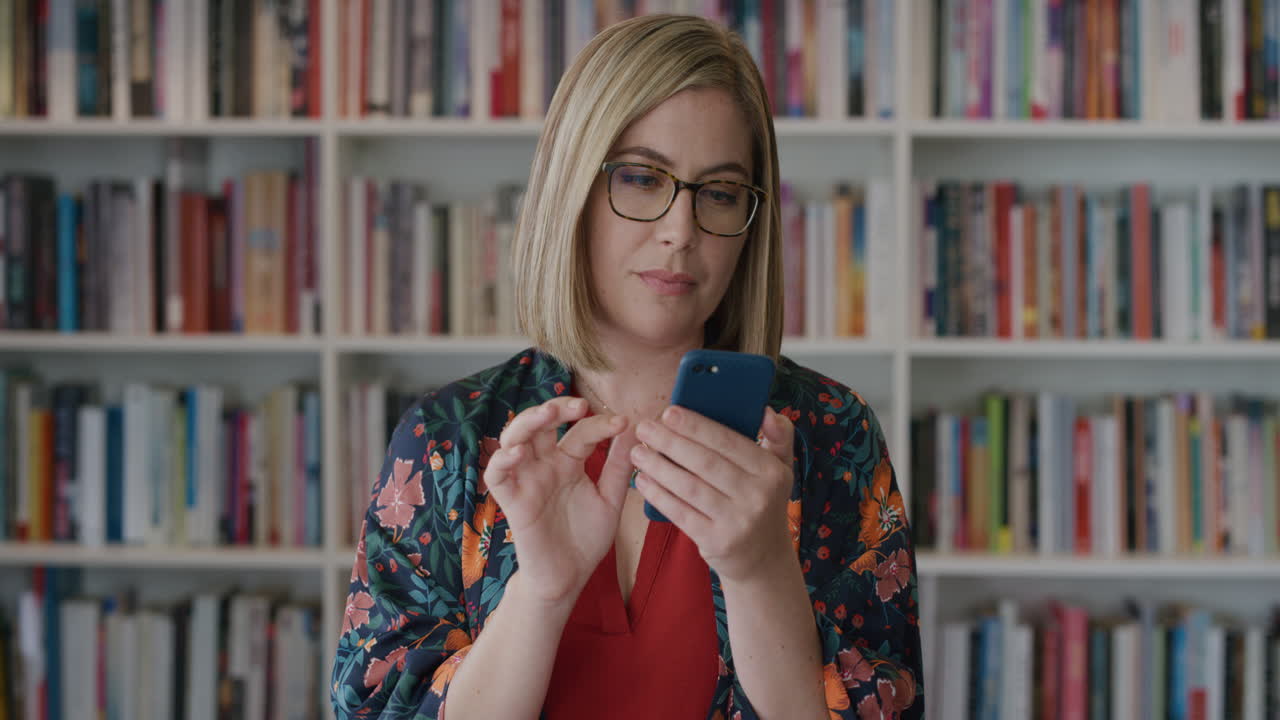 retrato de una joven empresaria que usa un teléfono inteligente navegando trabajando en línea leyendo mensajes en el teléfono móvil en el fondo de la estantería en cámara lenta