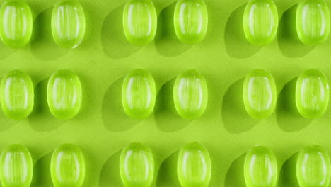 green mint mentol lollipops, candies, bonbons disappear on purple background. summer bright texture studio shot for store, supermarket, close up top view. children favorite sweets made of sugar.