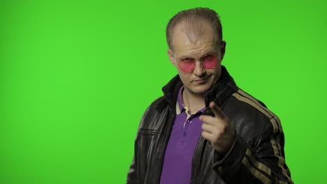 handsome rocker man in pink sunglasses pointing finger at you, looking at camera, making choice