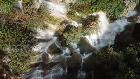 Erstaunliche-Luftaufnahme-Von-Oben-Nach-Unten-Auf-Den-In-Sonnenlicht-Getauchten-Kuang-Si-wasserfall