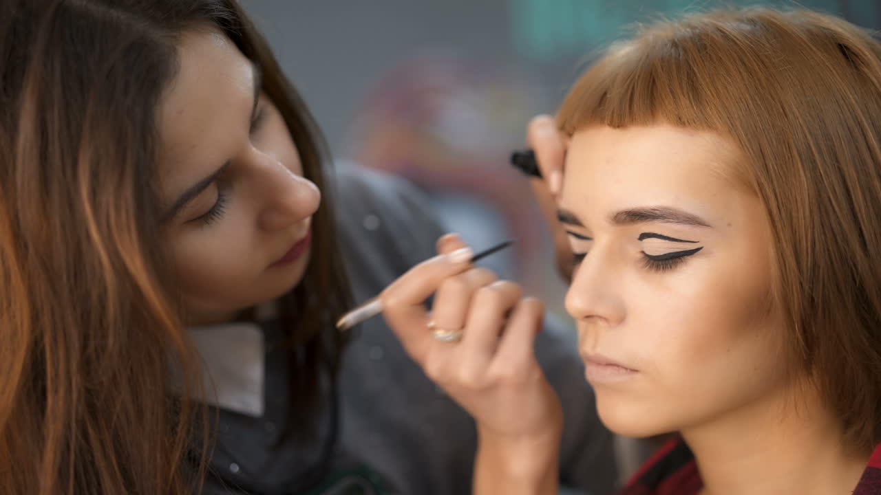 Make-up artist doing makeup. Female portrait. Close-up of hand near face.