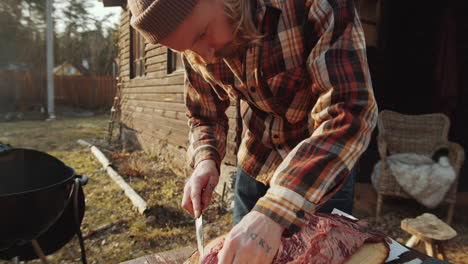 man cutting meat before grilling outdoors