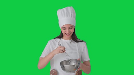 feliz india mujer chef profesional haciendo comida mientras explica pantalla verde