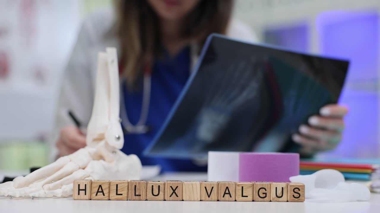 Wooden cubes spell term hallux valgus near foot skeleton model