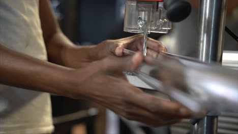 person using drill press to drill through a metal railing in preparation for making a large industrial lamp