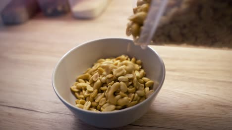 peanuts being poured into a white bowl