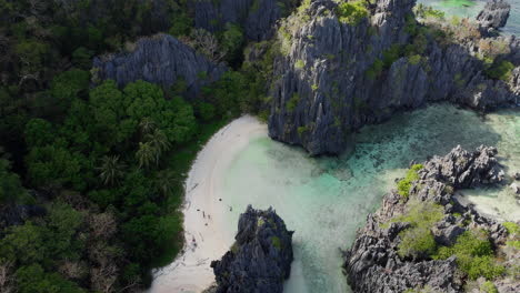 revealing aerial shot of isolated beach with white sand hidden by steep cliffs