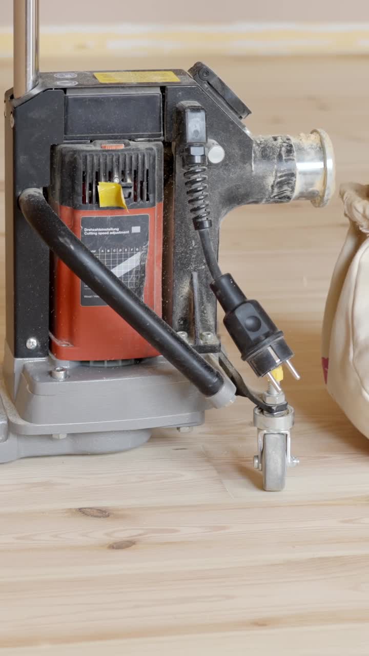 Levigatura dei bordi del pavimento con levigatrice manuale lungo il battiscopa, rimozione del sacchetto per la polvere, panoramica verticale che si sposta verso destra