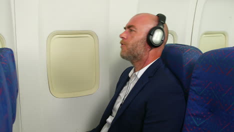 a happy man singing on a passenger airliner plane whilst wearing headphones listening to music