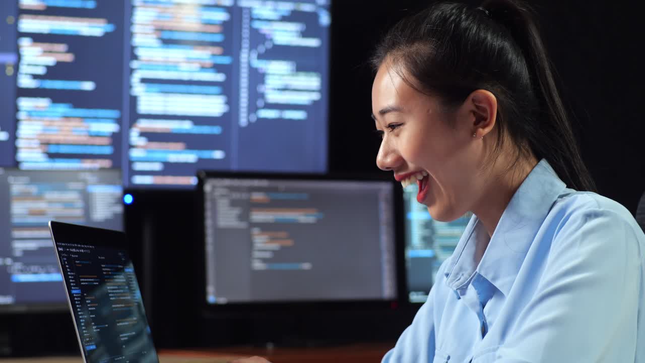 다중 모니터를 사용하여 노트북으로 코드를 작성하는 성공을 축하하는 아시아 여성 프로그래머의 가까운 측면 뷰 사무실의 터미널 윈도우 데스크에서 데이터베이스를 보여줍니다.
