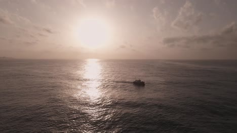 vista aérea de la silueta de un barco que viaja a través de un espectacular y reluciente paisaje marino al atardecer
