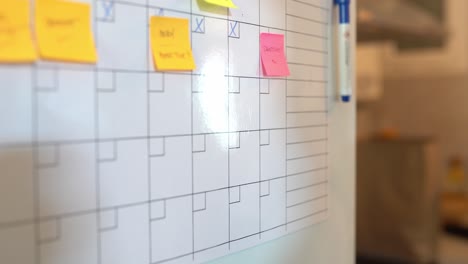 Crop-black-woman-taking-notes-in-planner-on-fridge