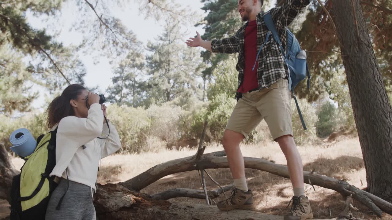 una feliz pareja afroamericana usando su teléfono inteligente y tomando fotos en el bosque, en cámara lenta.
