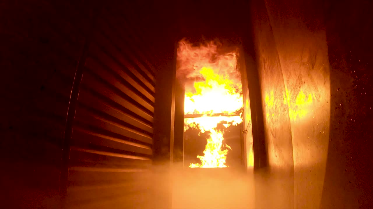 cámara lenta, punto de vista, de flashover durante el entrenamiento de bomberos dentro de un simulador en llamas