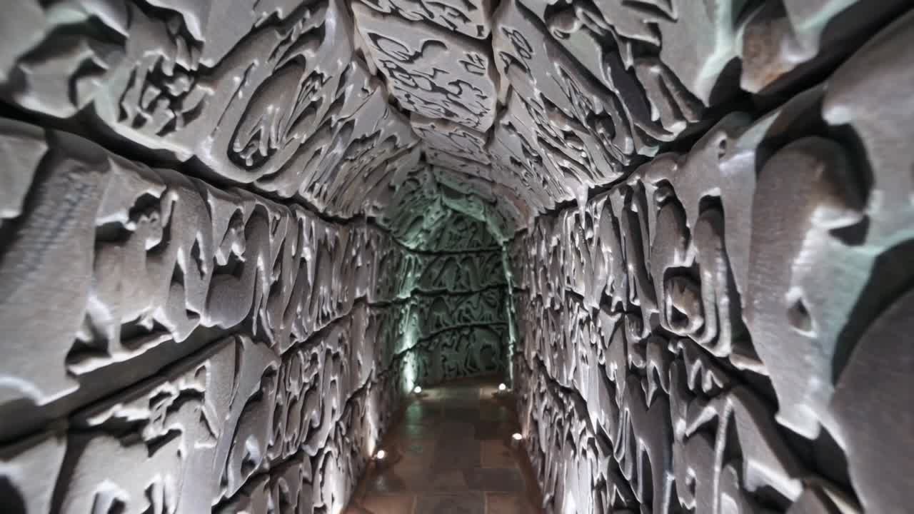 Intricate stone tunnel with textured walls illuminated by soft lighting, showcasing the gradual transition of light and shadow in a captivating architectural space