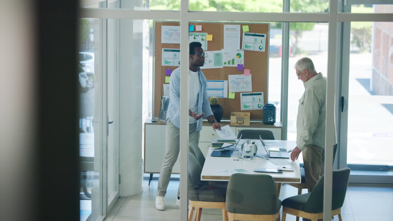 Two Businessmen Discussing Data and Strategy in a Modern Office Meeting