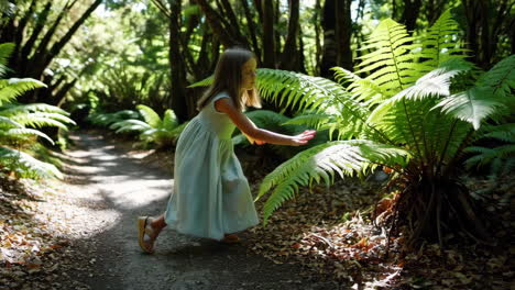 young girl exploring a sunlit fern forest path